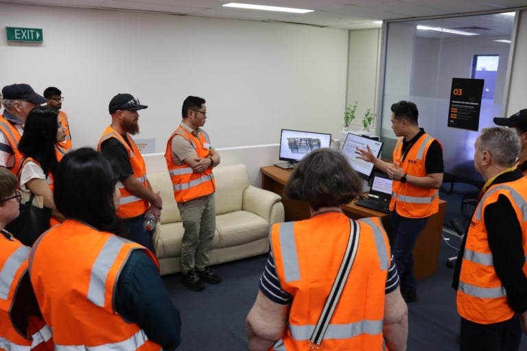 An iBuild team member showing guests a screen at the Delivery and Procurement station