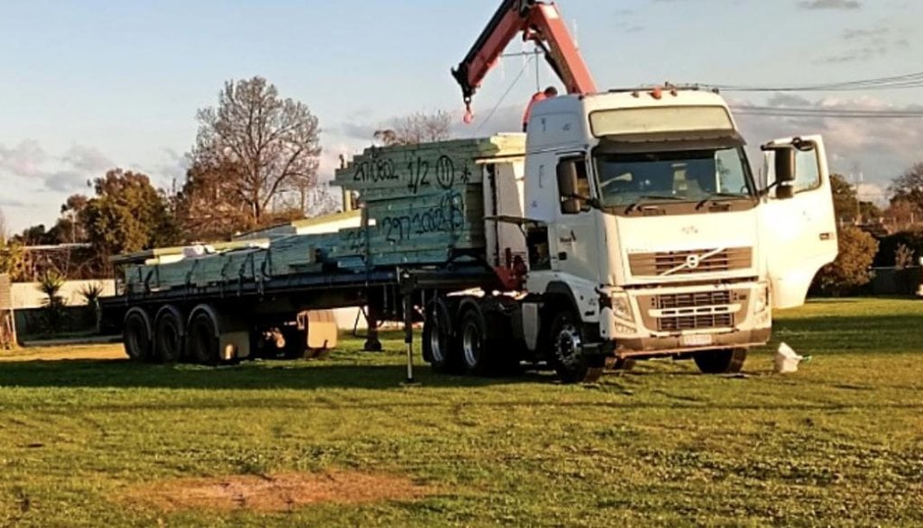 Crane truck delivering flat-packed timber wall frames and roof trusses for an iBuild kit home to a rural site